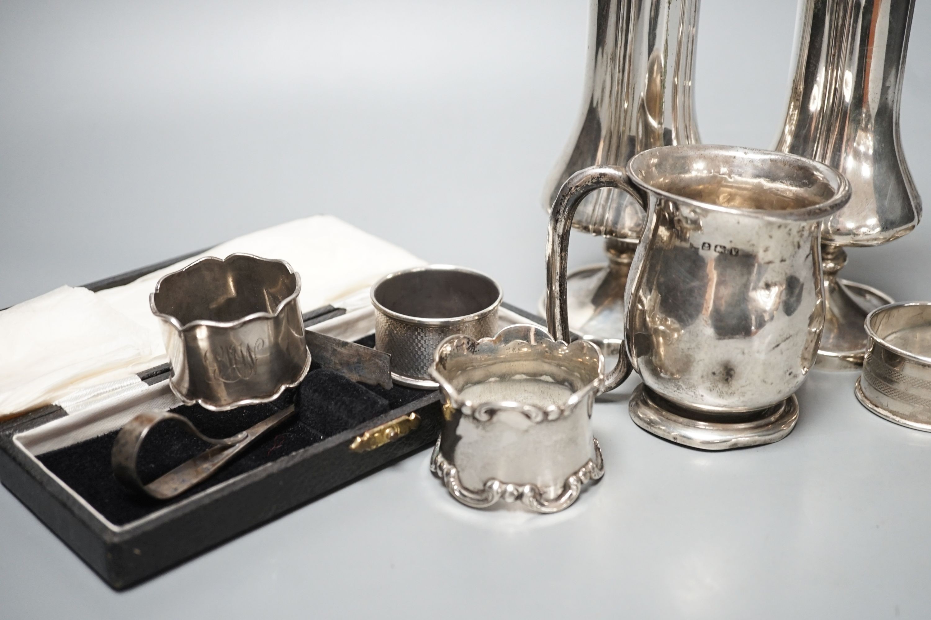 A pair of silver posy vases, a silver mug, a silver dish, five silver napkin rings, two button hooks and a cased silver pusher, weighable silver 9.5oz.